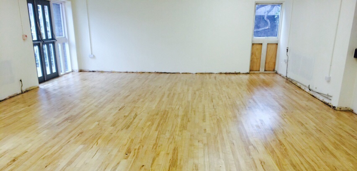 Wide-plank light hardwood floor sanding in commercial space